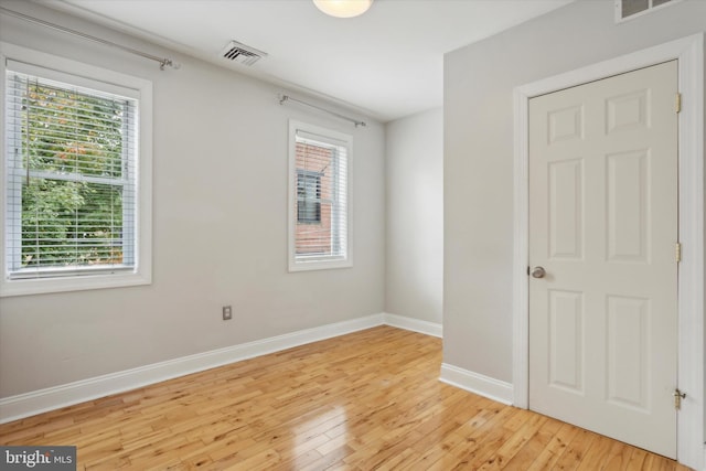 spare room featuring a wealth of natural light, visible vents, light wood-style flooring, and baseboards