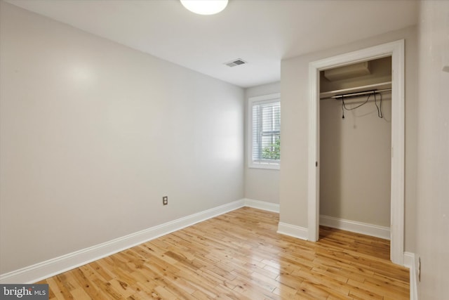 unfurnished bedroom featuring a closet, baseboards, visible vents, and light wood finished floors