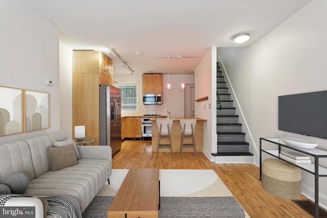 living room featuring stairway, visible vents, light wood-type flooring, and baseboards