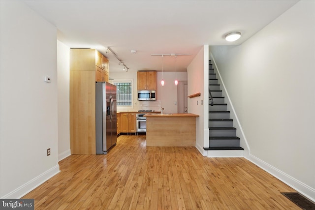 kitchen with visible vents, a peninsula, stainless steel appliances, decorative backsplash, and light wood-type flooring