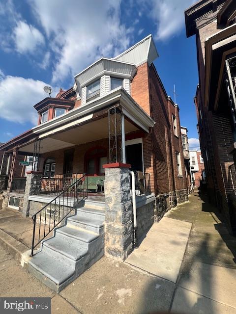 view of front of home featuring brick siding and a porch