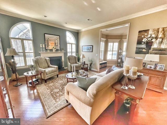 living area featuring baseboards, a fireplace with flush hearth, and crown molding