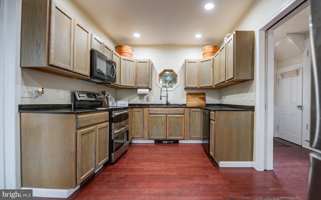 kitchen with dark countertops, a sink, recessed lighting, black appliances, and dark wood-style flooring