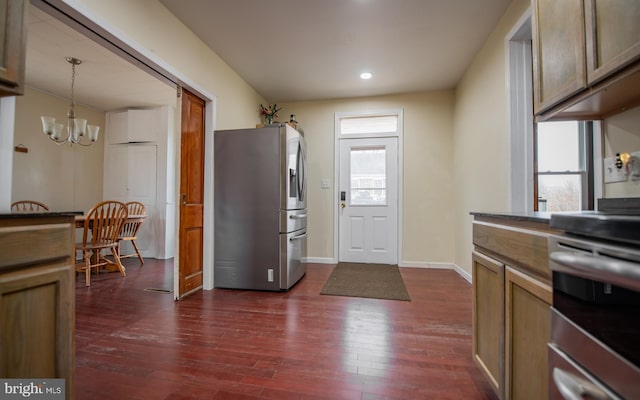 kitchen with dark wood-type flooring, dark countertops, stainless steel appliances, a chandelier, and hanging light fixtures