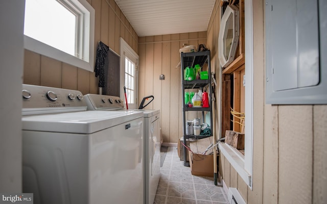 laundry room with wooden walls, a baseboard heating unit, light tile patterned floors, laundry area, and independent washer and dryer