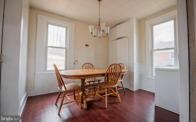 dining space featuring dark wood finished floors and a notable chandelier