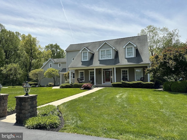 new england style home with a front lawn, covered porch, and a shingled roof