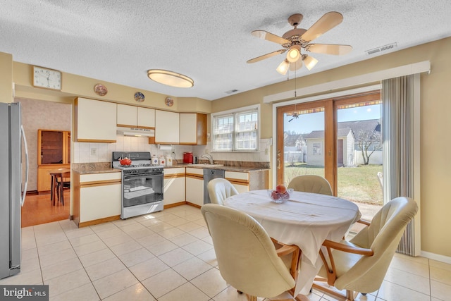 kitchen with visible vents, under cabinet range hood, appliances with stainless steel finishes, white cabinetry, and a sink