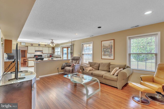 living room featuring recessed lighting, visible vents, a textured ceiling, and light wood-style flooring