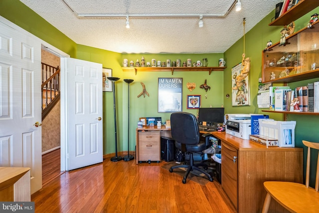 office featuring a textured ceiling, wood finished floors, and rail lighting