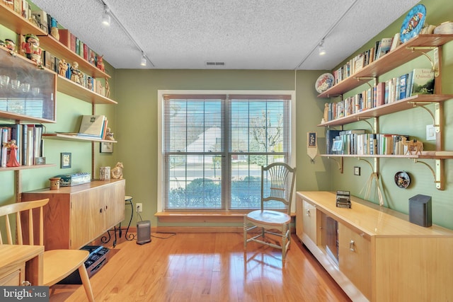 home office featuring rail lighting, light wood-style floors, and a textured ceiling