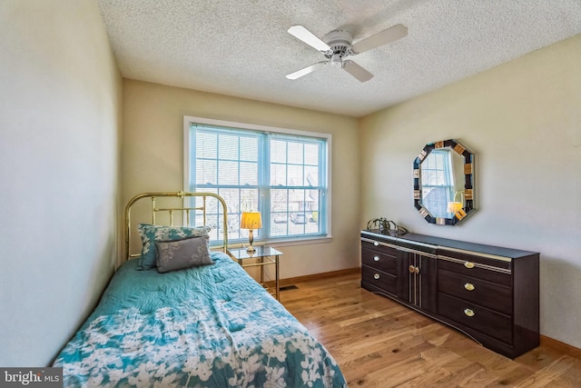 bedroom with a ceiling fan, baseboards, light wood finished floors, and a textured ceiling