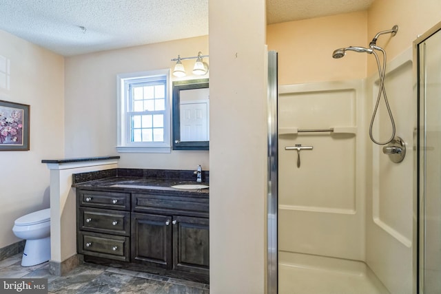 full bath featuring toilet, a stall shower, a textured ceiling, and vanity