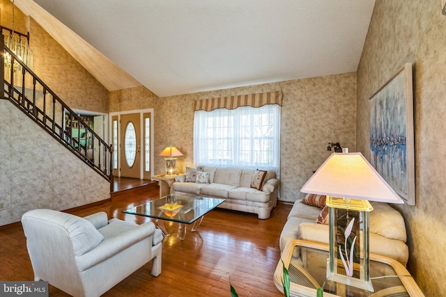 living area with stairway, high vaulted ceiling, and hardwood / wood-style floors