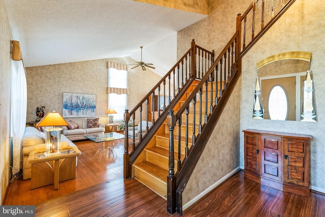 stairway featuring hardwood / wood-style floors, ceiling fan, baseboards, and high vaulted ceiling