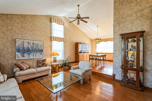 living area featuring ceiling fan with notable chandelier, wood finished floors, a wealth of natural light, and high vaulted ceiling