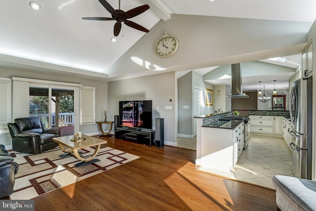 living area with baseboards, ceiling fan, beam ceiling, light wood-style flooring, and high vaulted ceiling