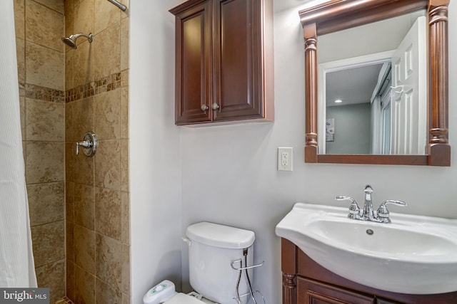 bathroom featuring toilet, vanity, and a tile shower