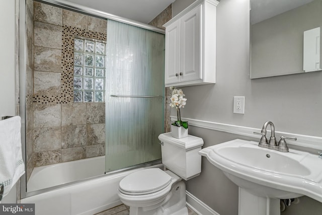 full bathroom with combined bath / shower with glass door, toilet, and a sink