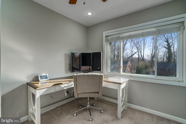 carpeted office space with a ceiling fan and baseboards