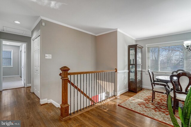 hall with hardwood / wood-style flooring, crown molding, an upstairs landing, and baseboards