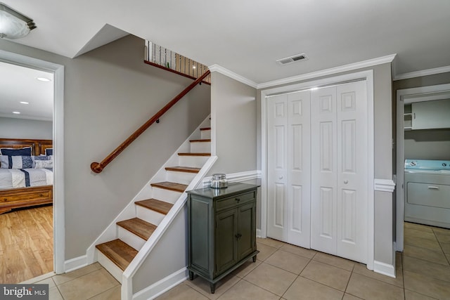 stairs featuring visible vents, crown molding, tile patterned flooring, baseboards, and washer / dryer