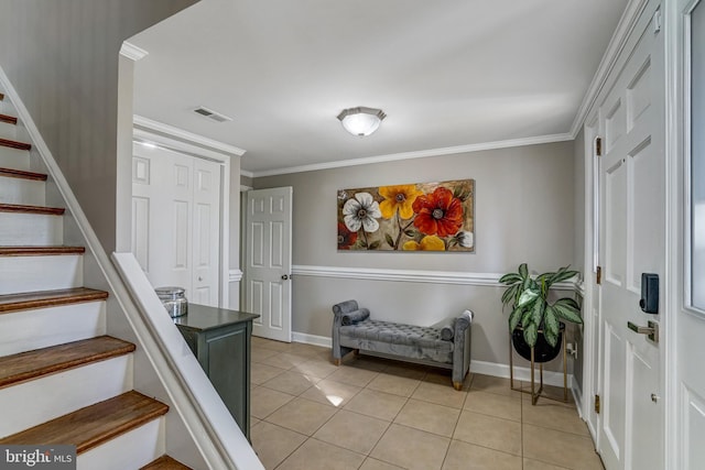 foyer entrance with visible vents, light tile patterned flooring, stairs, and crown molding