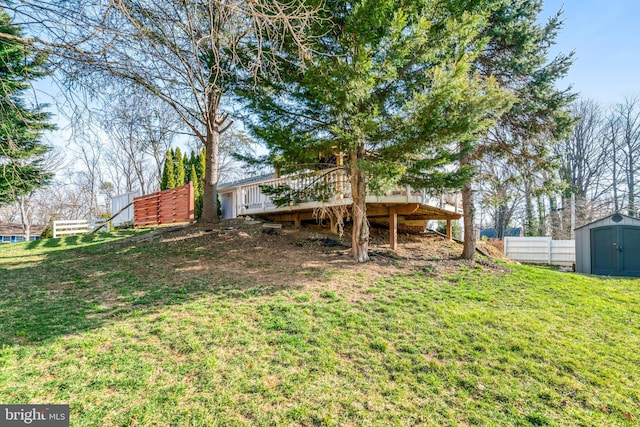 view of yard featuring a deck, fence, an outdoor structure, and a shed