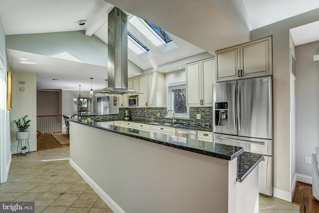 kitchen featuring lofted ceiling with skylight, tasteful backsplash, dark stone counters, appliances with stainless steel finishes, and light tile patterned floors