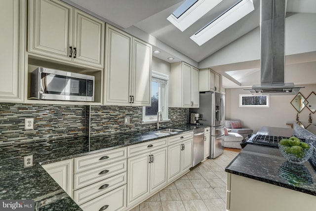 kitchen with vaulted ceiling with skylight, cream cabinets, stainless steel appliances, and island range hood