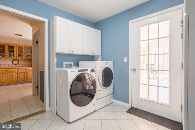 laundry room featuring light tile patterned floors, washer and dryer, cabinet space, and baseboards