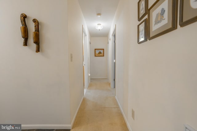 hallway featuring baseboards and light colored carpet