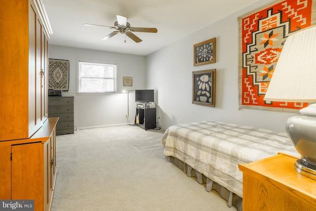 bedroom with a ceiling fan, baseboards, and light carpet