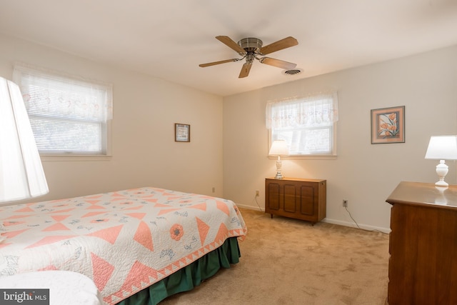 bedroom with visible vents, baseboards, light colored carpet, and ceiling fan