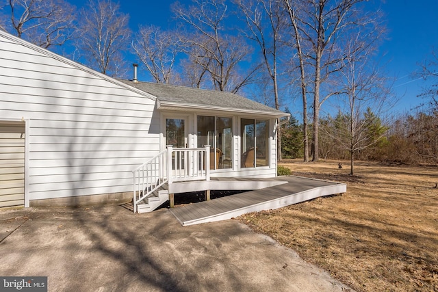 entrance to property with a deck and roof with shingles