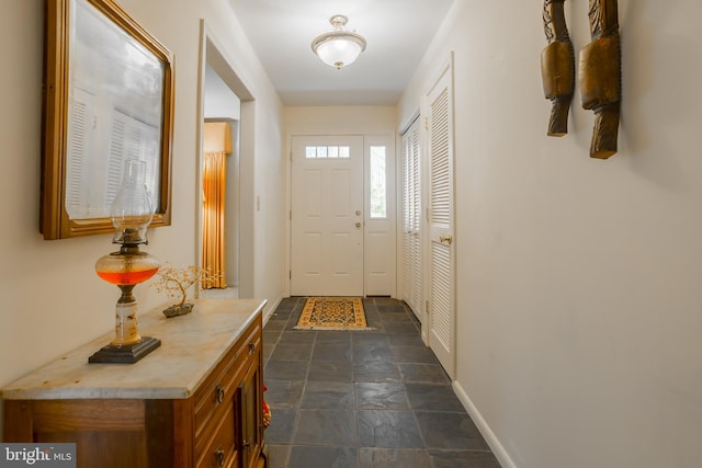 doorway with stone finish floor and baseboards