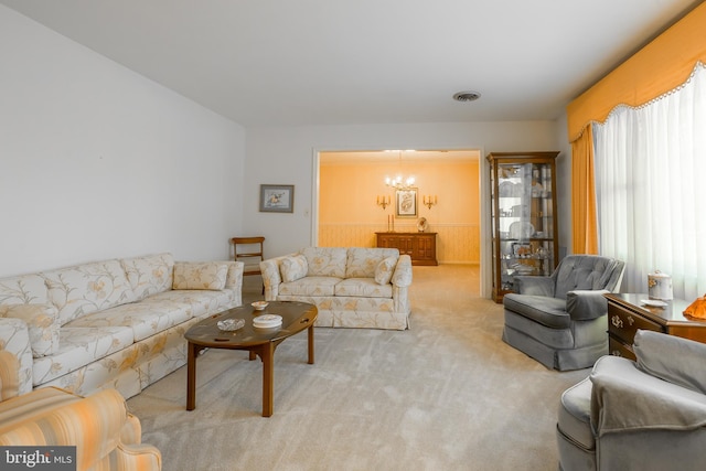 living area featuring visible vents, a wainscoted wall, carpet, and a chandelier