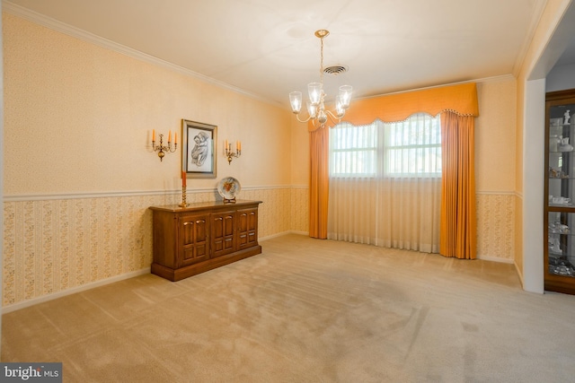 carpeted spare room with a notable chandelier, wallpapered walls, and ornamental molding