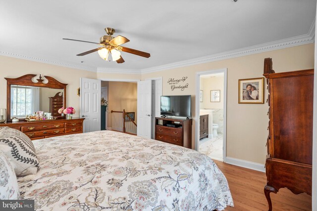 bedroom with crown molding, baseboards, wood finished floors, ensuite bath, and a ceiling fan