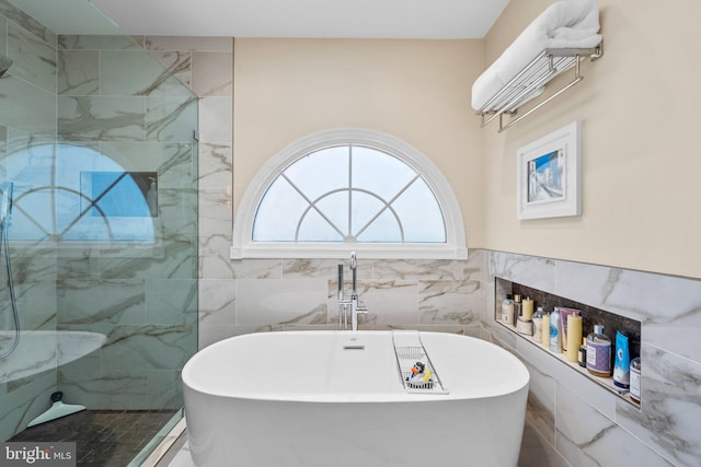 full bath featuring wainscoting, a freestanding bath, tile walls, and walk in shower