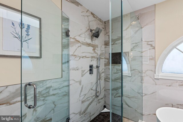 full bath with a marble finish shower, tile walls, and a freestanding tub