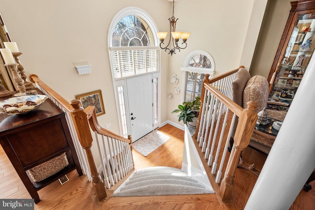 foyer entrance featuring baseboards, a chandelier, stairway, a towering ceiling, and wood finished floors