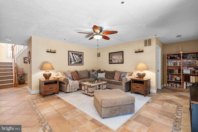 living room featuring visible vents, baseboards, a textured ceiling, and stairway