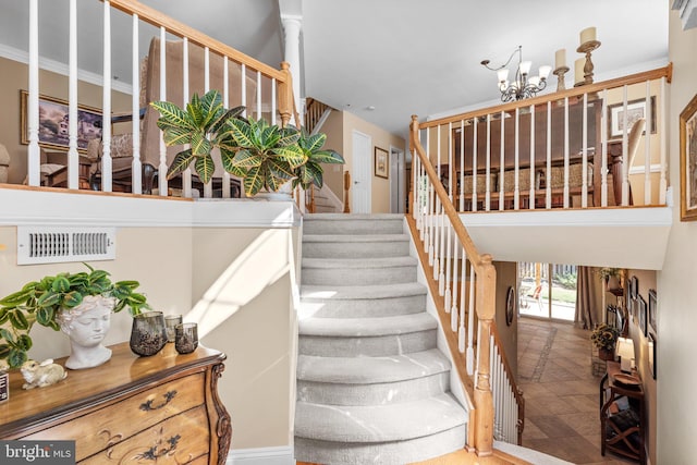 stairway with an inviting chandelier and visible vents