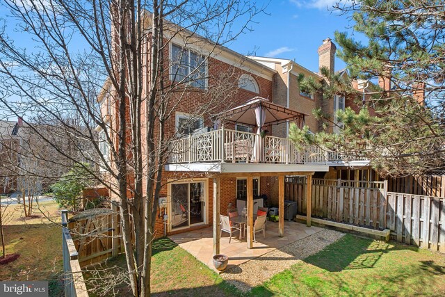 back of property with a patio, brick siding, a chimney, and fence