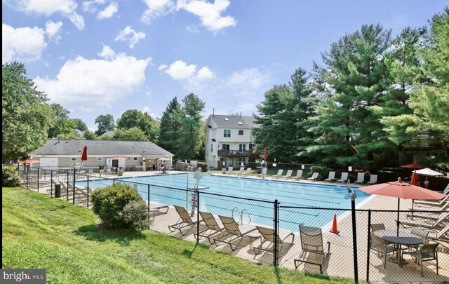 community pool with a patio, a yard, and fence