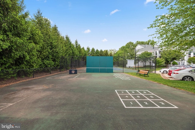 view of home's community with uncovered parking, a tennis court, shuffleboard, and fence