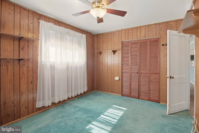 unfurnished bedroom featuring a closet, wooden walls, and carpet