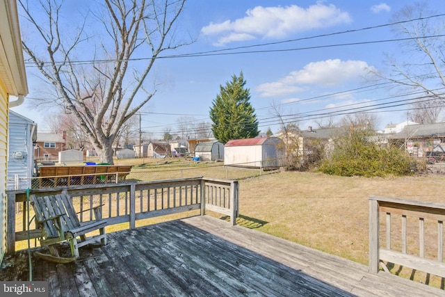 wooden deck with an outbuilding, a lawn, and fence