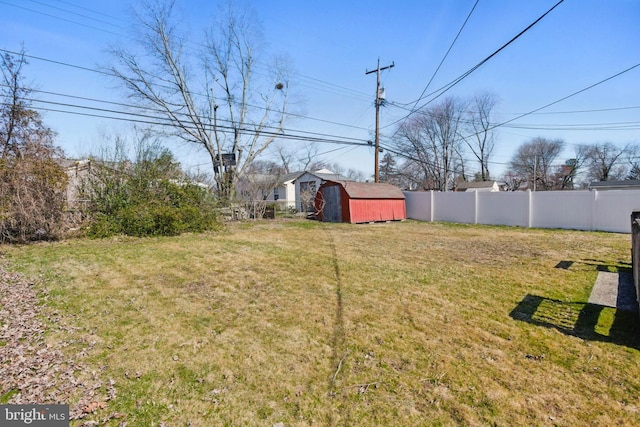 view of yard featuring an outbuilding, fence, and a shed